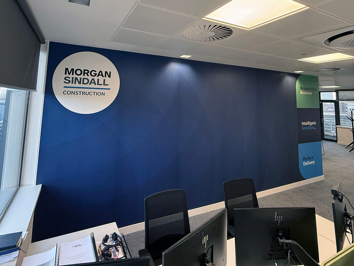 Morgan Sindall office featuring a blue branded wall mural with the company logo and three corporate values