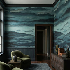 Roerich Hills wallpaper mural shown in reading corner with green armchairs