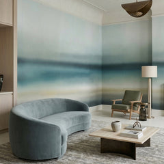 Rotko Blush wallpaper mural shown in living room with blue curved sofa and wood chair