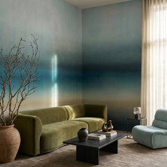 Rotko Blush wallpaper mural shown in living room with green sofa and blue chair