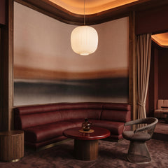 Rotko Dawn wallpaper mural shown in living room with curved burgundy sofa